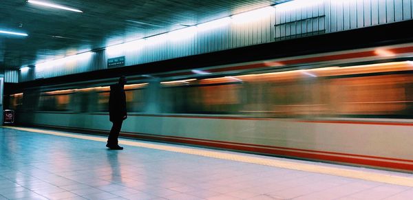 Man standing by train at railroad station platform