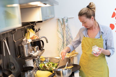 Woman having food in kitchen at home