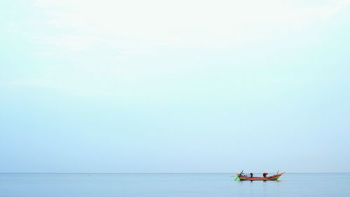 Boat sailing in sea against clear sky