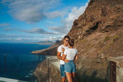 Rear view of woman standing on mountain against sky