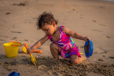 Side view of girl playing with sand at beach