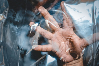 A hand struggling behind a transparent plastic sheet