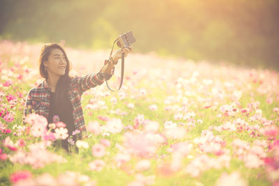 Young woman photographing with mobile phone outdoors