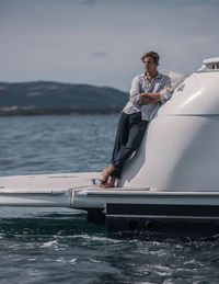 Man standing on boat in sea against sky