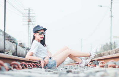 Portrait of young woman sitting on railroad track