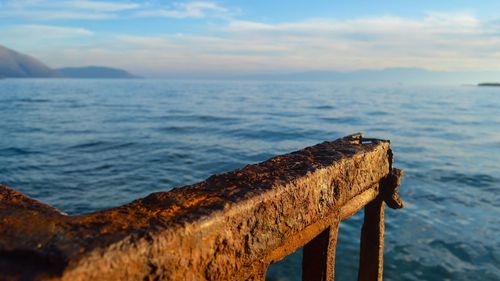 Close-up of rusty metal on beach against sky