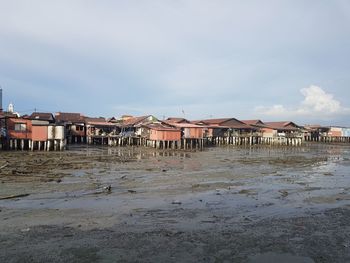 Houses on beach by buildings against sky