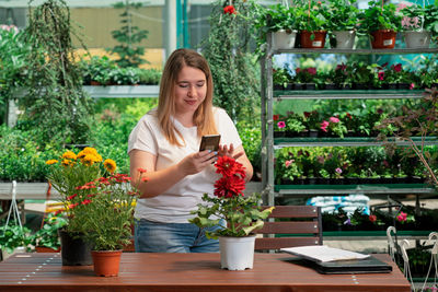 Young woman photographing potted plant