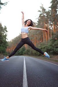 Woman with arms outstretched against sky