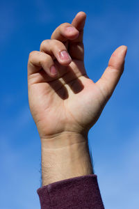 Close-up of human hand against sky