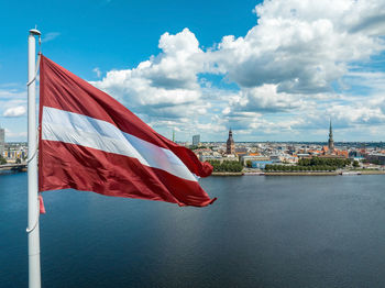 Latvian flag with the dome cathedral and an old town in the background