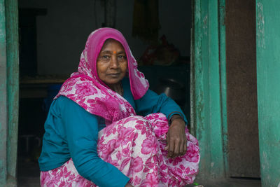 Portrait of woman wearing sari sitting at the door of the house