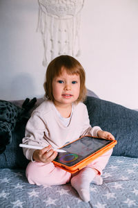 Girl using digital tablet sitting on bed