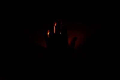 Close-up of silhouette hand against black background