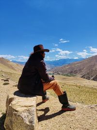 Side view of man sitting on rock