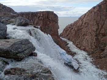 Rock formations by sea against sky