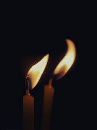 Close-up of burning candles against black background