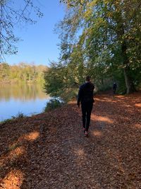 Rear view of woman walking on lake against trees