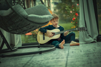 Cute boy playing guitar at home