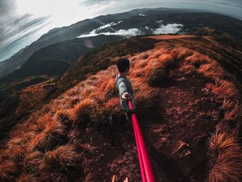 Side view of man holding monopod while standing on mountain