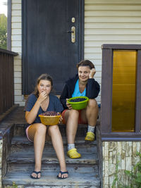 Portrait of mother and daughter sitting at porch 