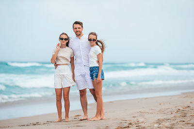 Friends standing at beach against clear sky