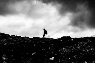 Silhouette man standing on rock on land against sky