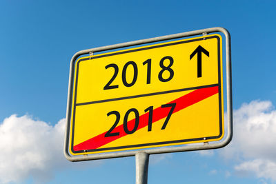 Low angle view of road sign against blue sky