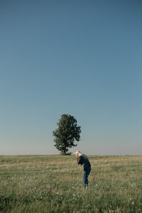 Side view of woman standing on field against clear sky