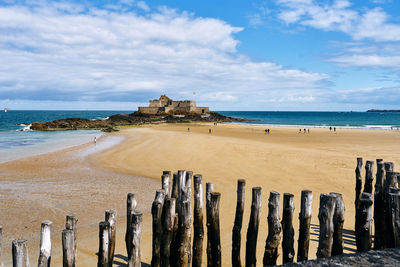 Scenic view of beach and andient castle ruin against sky at st malo in the bretagne