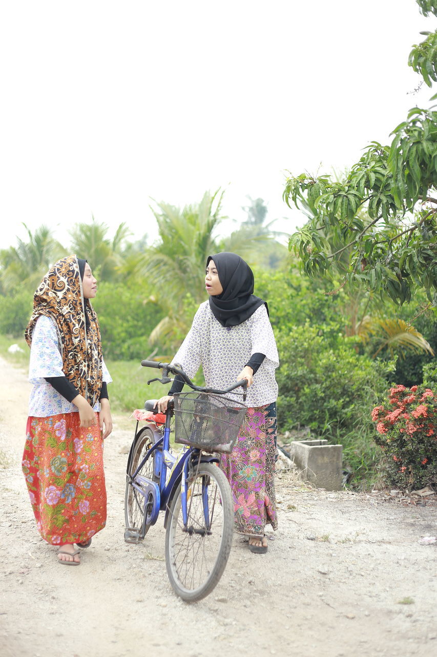 FULL LENGTH REAR VIEW OF WOMAN RIDING BICYCLE