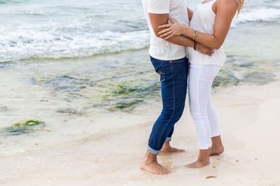 Low section of friends standing on beach