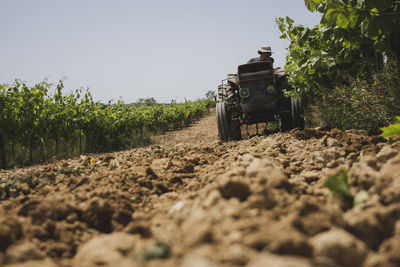 Surface level shot of farmer plowing field using tractor against sky during sunny day