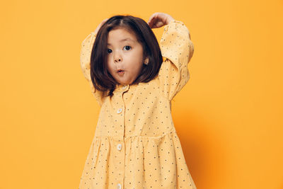 Portrait of young woman against yellow background