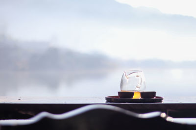 Morning cup of hot tea with lake background at sunrise.