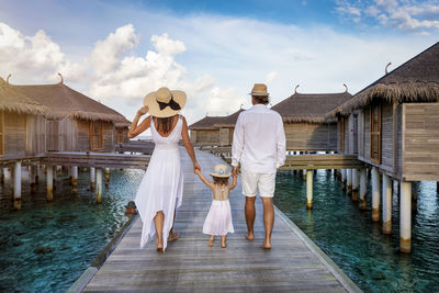 Rear view of family walking on pier against houses