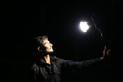 Man looking at illuminated light against black background