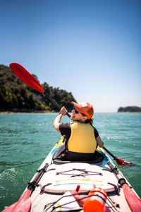 Woman paddling kayak under clear skies in abel tasman national park