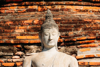 Statue of buddha against brick wall of building