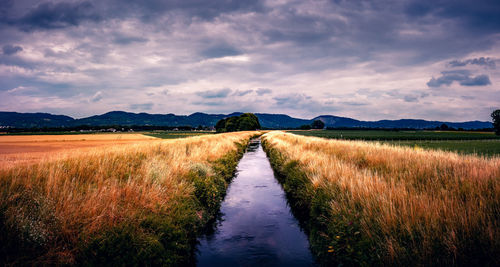 Road amidst field against sky