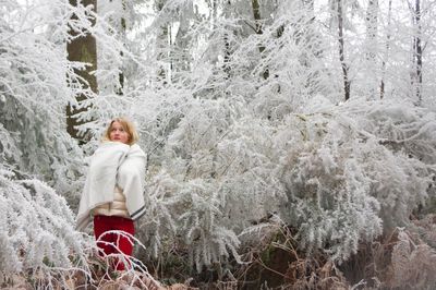 Girl wrapped in blanket against frozen trees