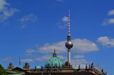 Communications tower in city against blue sky