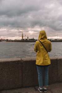 Woman in yellow raincoat looking on dramatic landscape. tourist looking on  peter and paul cathedral