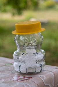 A glass salt shaker in the shape of a bear in a yellow hat. 