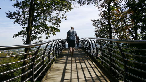 Rear view of man walking towards woman on footbridge