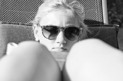 Close-up of young woman reading book while sitting on chair in yard