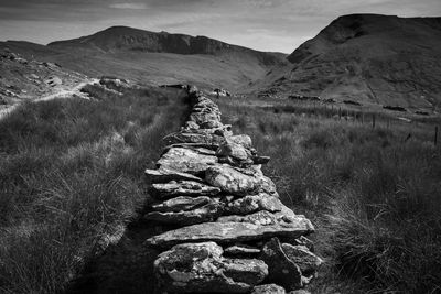 Stack of rocks on field against mountain