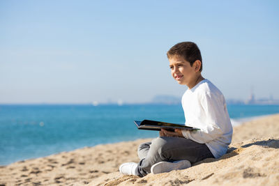 Little kid reading a book on the beach