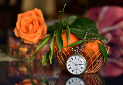 Close-up of rose bouquet and old pocket watch on table at home