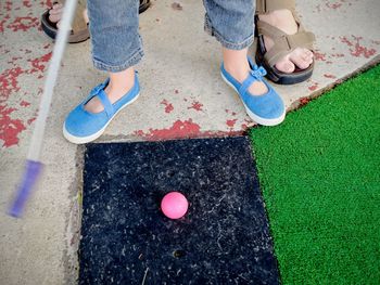 Low section of adult and child playing mini golf